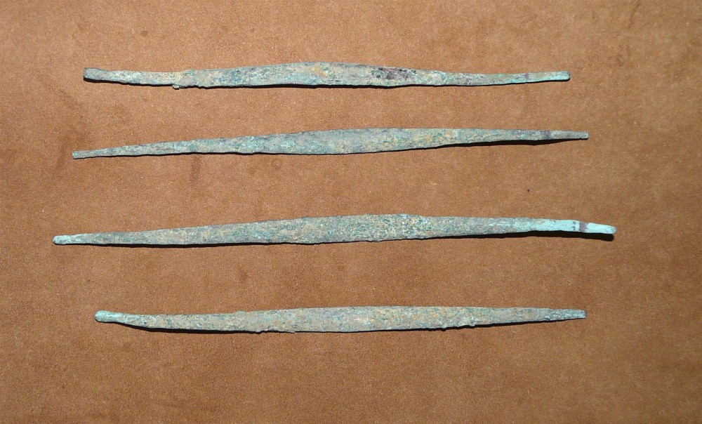 Abb.3: Vier flache, stabförmige, etwas gewellte, spitz auslaufende Kupferbarren der Sundi. Länge zwischen 17 und 19,5 cm, Gewicht von 14,6 bis 20,7 g.